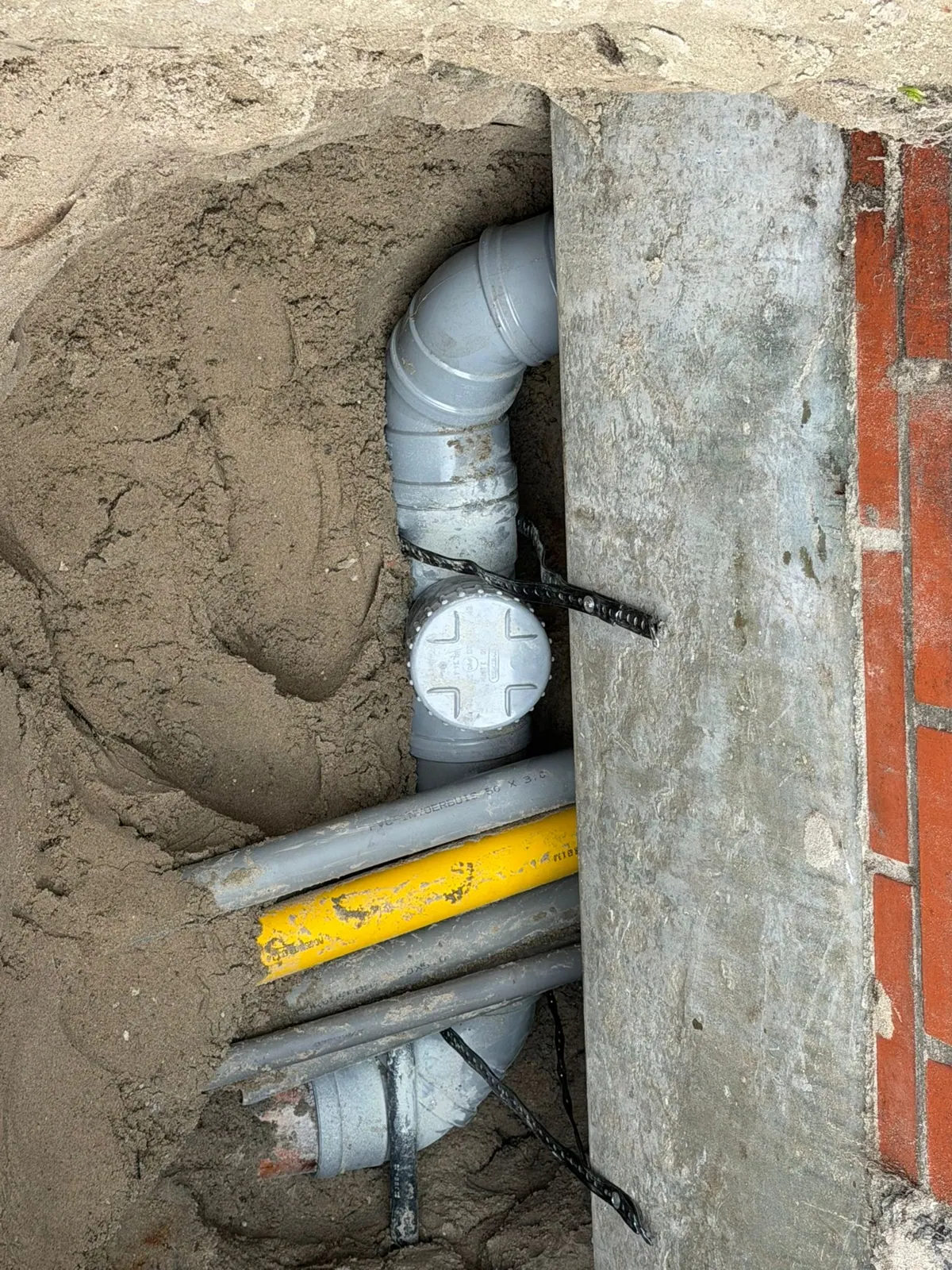 Nieuwe PVC-aansluiting met ontstoppingsstuk tussen kabels en leidingen