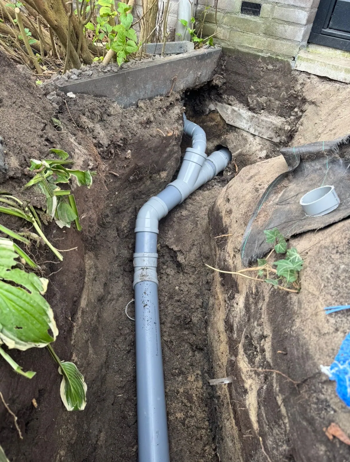 Nieuwe PVC-riolering met broekstuk in de voortuin