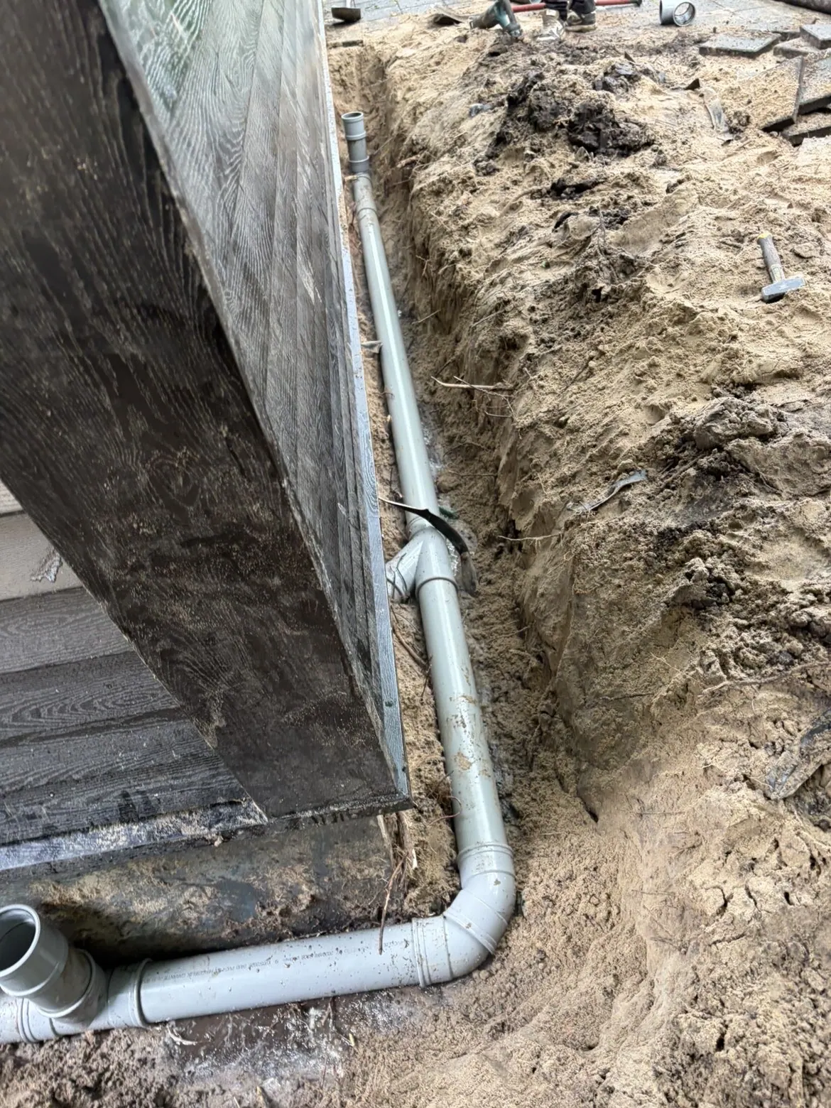 PVC-riolering langs een houten gevel