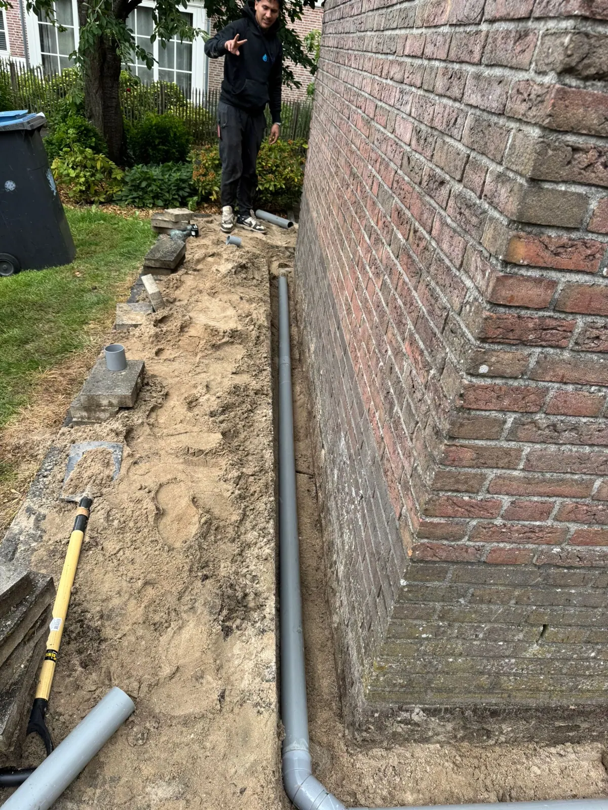Monteur legt nieuwe PVC-leiding langs de gevel